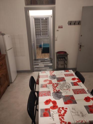 a room with a table with red flowers on it at Lilas, Gîte Saint Antoine, Orcival, Entre Sancy et Volcans. in Orcival