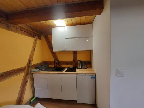a small kitchen with white cabinets in a attic at Agroturystyka Ranczo Gościszów in Nowogrodziec
