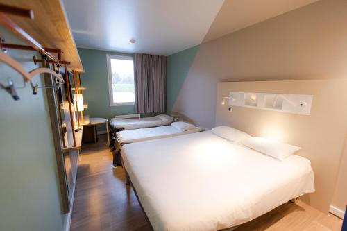 a hotel room with two beds and a window at ibis budget Albertville in Gilly-sur-Is&egrave;re