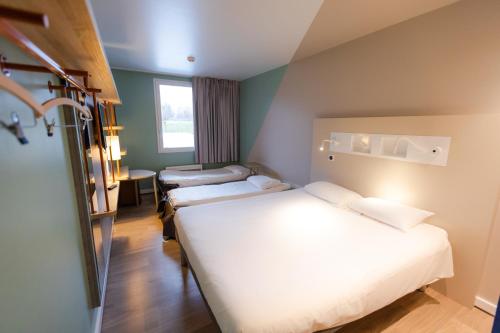een hotelkamer met 2 bedden en een raam bij ibis budget Albertville in Gilly-sur-Isère