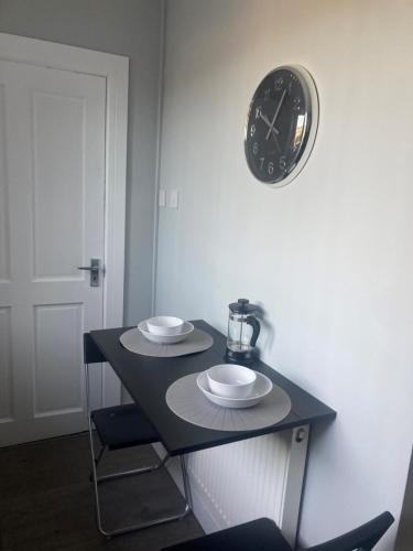 stół z dwoma talerzami i zegarem na ścianie w obiekcie Teviot View Apartment w mieście Hawick