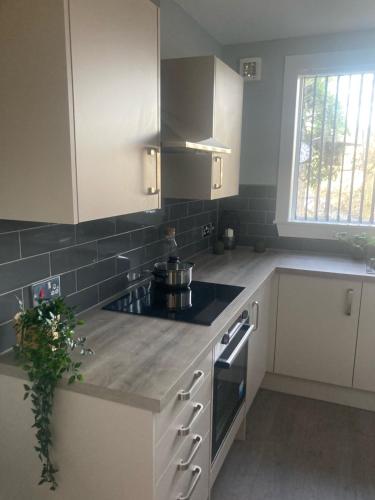 una cucina con armadi bianchi e piano cottura di Teviot View Apartment a Hawick