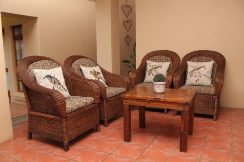 four wicker chairs and a table in a room at Del Roza Guest House in Middelburg