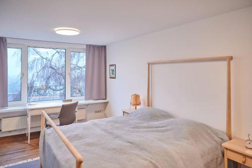 a bedroom with a bed and a desk and two windows at zeitweise[.]haus Denkerhaus und Stadtoase in Weingarten