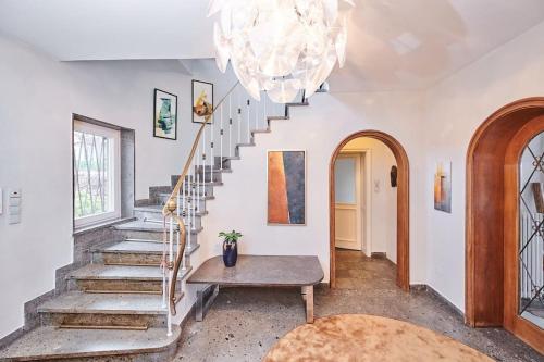 a living room with a staircase and a chandelier at zeitweise[.]haus Denkerhaus und Stadtoase in Weingarten