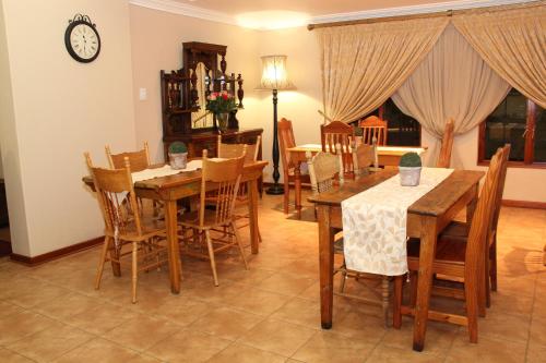 a dining room with tables and chairs and a clock at Del Roza Guest House in Middelburg