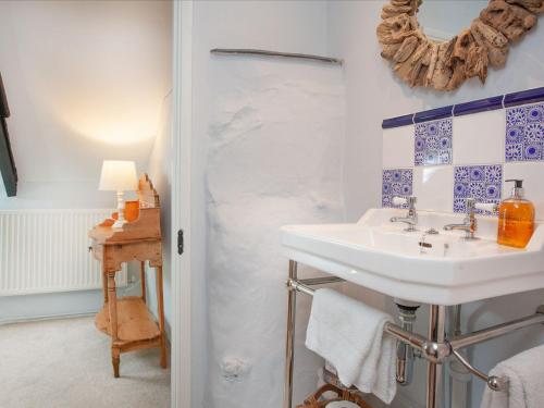 a bathroom with a sink and blue and white tiles at The Annexe - Tbh in Crackington Haven