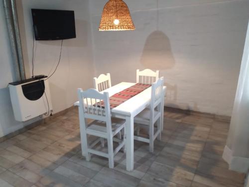 a white table with three chairs and a tv at Departamento Tunuyán in Tunuyán
