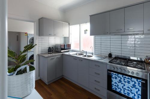 a kitchen with white cabinets and a stove top oven at Art deco inner city comfort in Bendigo
