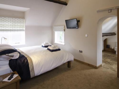 a bedroom with a bed and a tv on the wall at Morton Grange Coach House - E5557 in Ellesmere