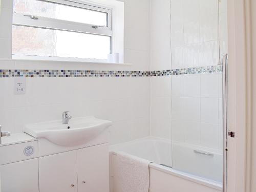 a white bathroom with a sink and a shower at Brambles Cottage in Yarmouth