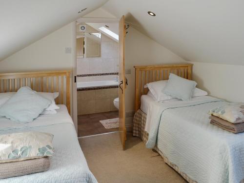 a attic bedroom with two beds and a bathroom at Cherry Blossom Cottage in Birstwith