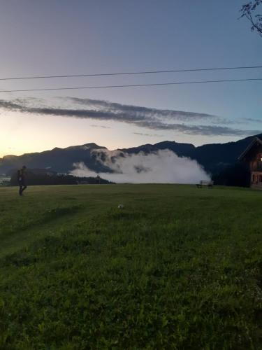 a person walking in a field with mountains in the background at Sonnleit'n Zimmer 6 in Abtenau