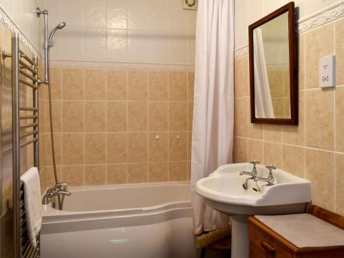 uma casa de banho com um lavatório e uma banheira e um lavatório em Coach House em Loddiswell
