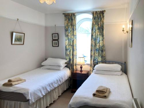 two twin beds in a room with a window at Coach House in Loddiswell