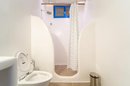 a white bathroom with a toilet and a shower at Conch Resort Luxury Private Pool Suites in Puducherry