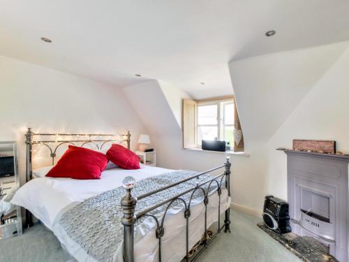 a bedroom with a bed with red pillows and a fireplace at Tom Cottage in Wing