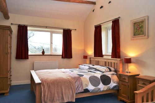 a bedroom with a bed and two windows at Netherend in Threlkeld