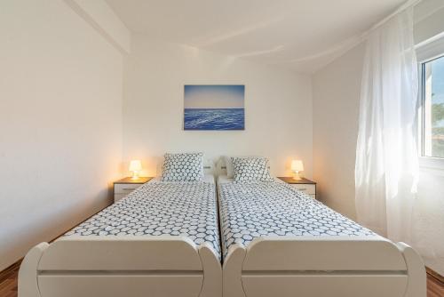 a white bedroom with a large bed with two lamps at Apartmani Luka in Vir