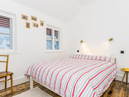 a white bedroom with a bed and two windows at Ty Macsen in Llanwnda