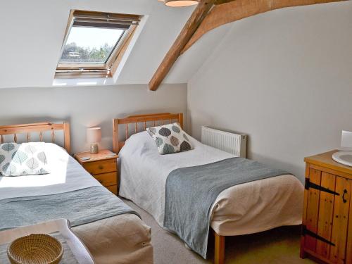 a attic bedroom with two beds and a window at The Cottage in Great Ellingham