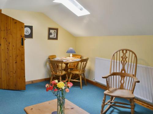 una habitación con mesa, sillas y un jarrón de flores en Holly Cottage en Richmond