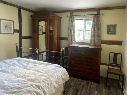Longhope的住宿－小屋鄉村別墅，一间卧室配有一张床、一个梳妆台和一扇窗户。