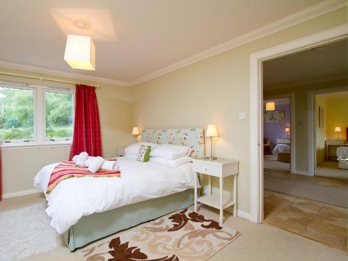 a bedroom with a bed with a red curtain at Carness West in North Ballachulish