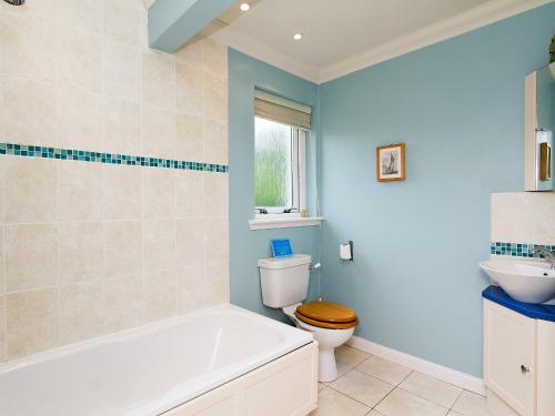 a bathroom with a tub and a toilet and a sink at Carness West in North Ballachulish
