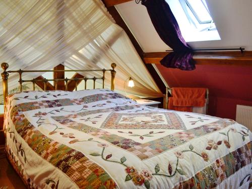 a bedroom with a bed with a quilt on it at La Caleche in Cirencester