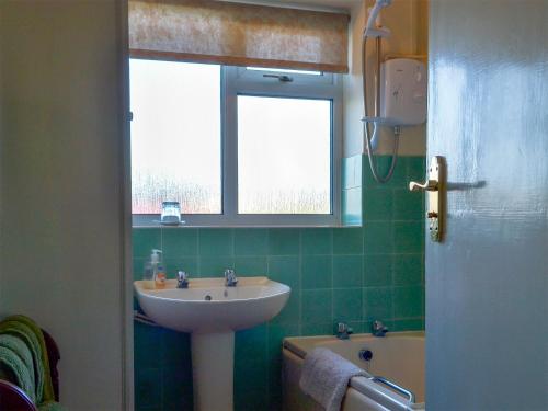 een badkamer met een wastafel, een bad en een raam bij The Bungalow in Pentrich