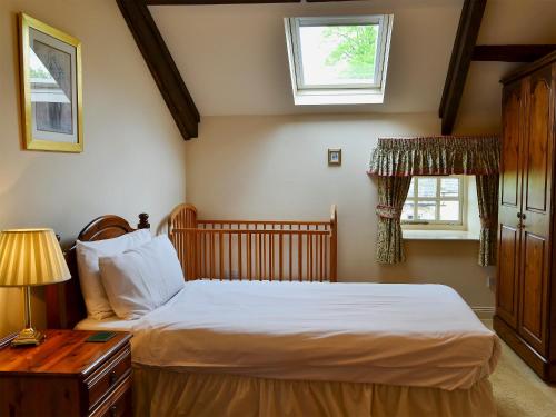 a bedroom with a bed and a table and two windows at Primula Patch-mjc in Akeld
