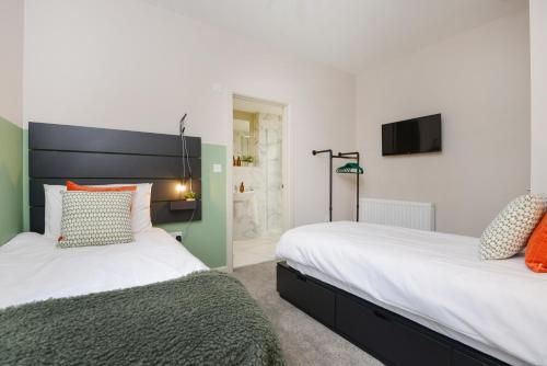 two beds sitting next to each other in a bedroom at Apt Three - Private Car Park - 3 shower rooms - by Ocean City Retreats in Plymouth