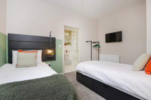 two beds sitting next to each other in a bedroom at Apartment Three - Free Private Car Park - sleeps 6 - 3 shower rooms - by Ocean City Retreats in Plymouth