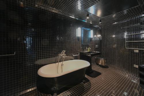 La salle de bains est pourvue de carrelage noir, d'une baignoire et d'un lavabo. dans l'établissement Exceptional suite in saint Germain des Près (Montana4), à Paris