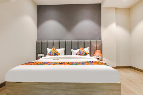a bedroom with a large white bed with colorful pillows at FabHotel Prime K9 Grand in Ludhiana