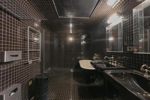 a black tiled bathroom with a sink and a toilet at Sublime Suite à saint Germain des Près (Montana 7) in Paris