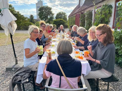 Købmandsgården في Ballen: مجموعة من الناس يجلسون على طاولة طويلة لتناول الطعام