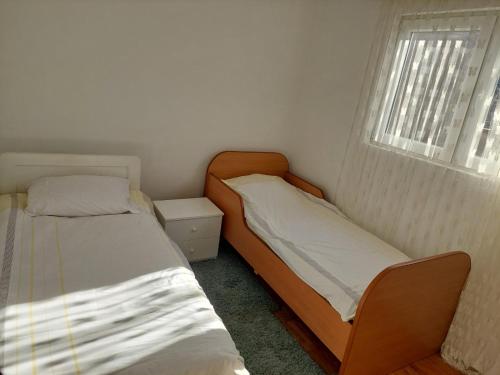 2 Betten in einem kleinen Zimmer mit Fenster in der Unterkunft Apartment Bitola in Bitola