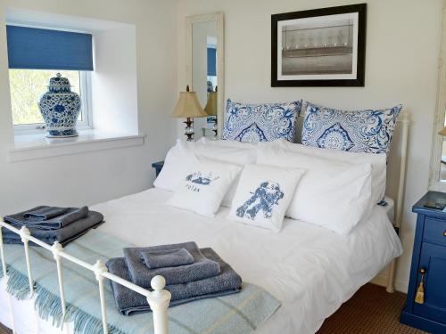 um quarto com uma cama branca com almofadas azuis e brancas em The Wee Hoose em Achnahanat