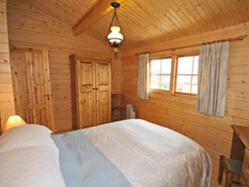 een slaapkamer met een wit bed in een houten kamer bij Field Lodge - E4380 in Overseal