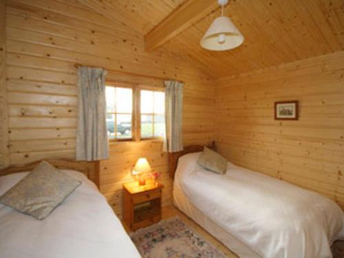 a bedroom with two beds in a log cabin at Field Lodge - E4380 in Overseal