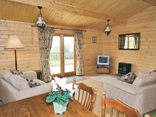 a living room in a log cabin with a fireplace at Field Lodge - E4380 in Overseal