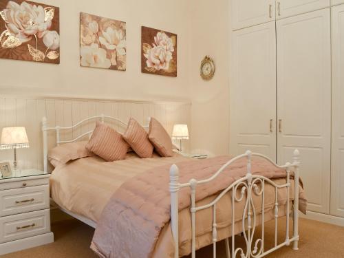 1 dormitorio con cama blanca y almohadas rosas en Bwthyn Bach en Caeathro