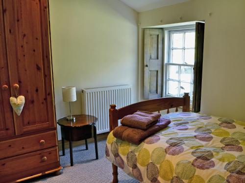 een slaapkamer met een bed, een tafel en een raam bij Waulkmill Cottage in Carronbridge
