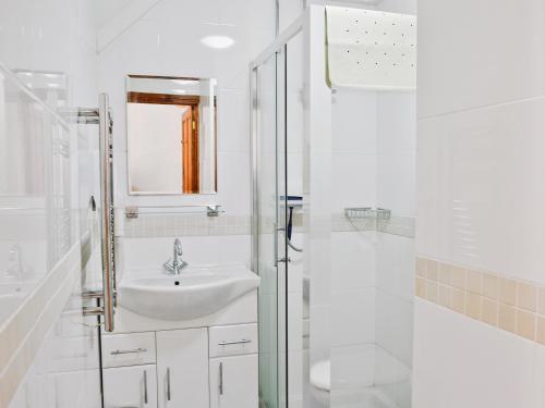 a white bathroom with a sink and a shower at Rose Cottage - 30502 in West Firle