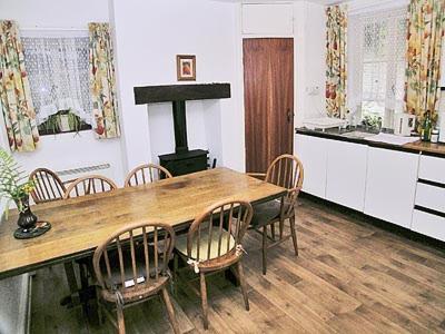 uma cozinha com uma mesa e cadeiras de madeira e um fogão em Tacker Street Cottage em Withycombe