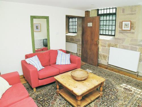HazelwoodにあるTurpins Cottageのリビングルーム(赤いソファ、コーヒーテーブル付)