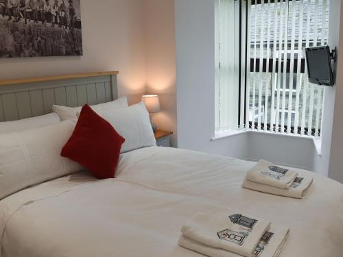 a white bed with a red pillow and a window at Jamaica Villa in Madron