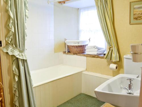 a bathroom with a bath tub and a sink at Redmayne Cottage in Orton